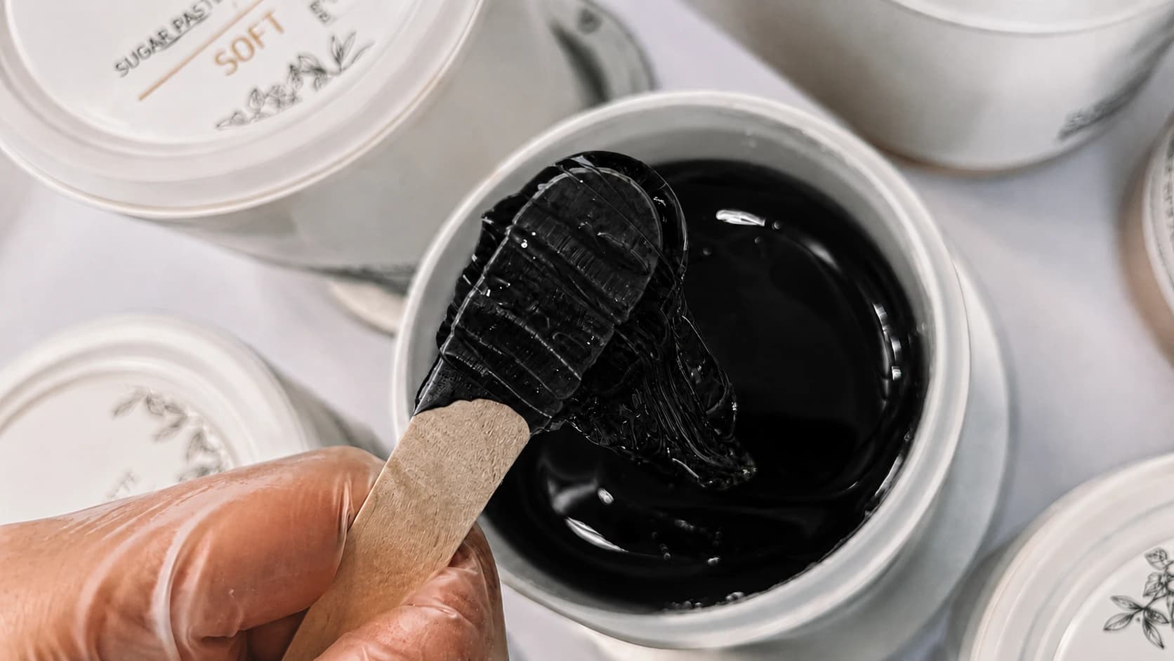 Warm black waxing gel dripping from wooden applicators